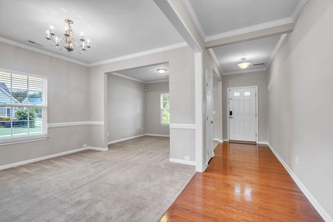 A room with a chandelier, a door, and a window.