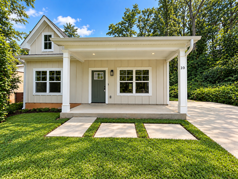 A small house with a white porch and a green door.
