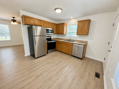 A kitchen with wooden cabinets and a stainless steel refrigerator.