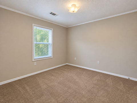 A room with a carpeted floor and a window.