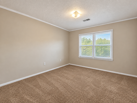 A room with a carpeted floor and a window with blinds.