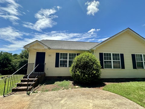 A house with a blue sky and clouds in the background.
