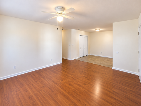 A room with a ceiling fan and wooden flooring.