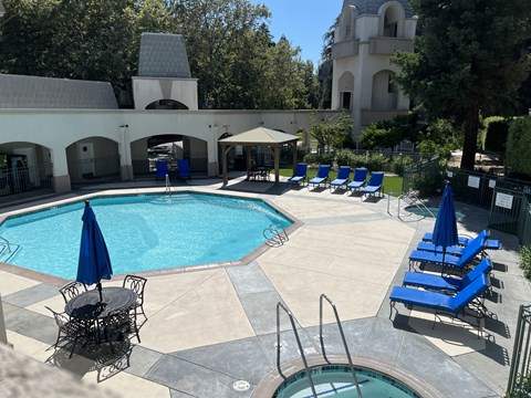 a swimming pool with blue lounge chairs and umbrellas