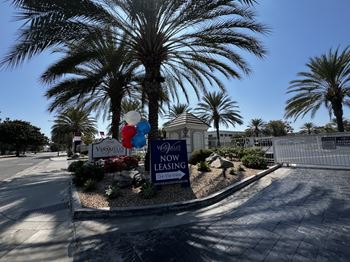 A sign in front of a palm tree reads "Vespa Villas Now Leasing.".