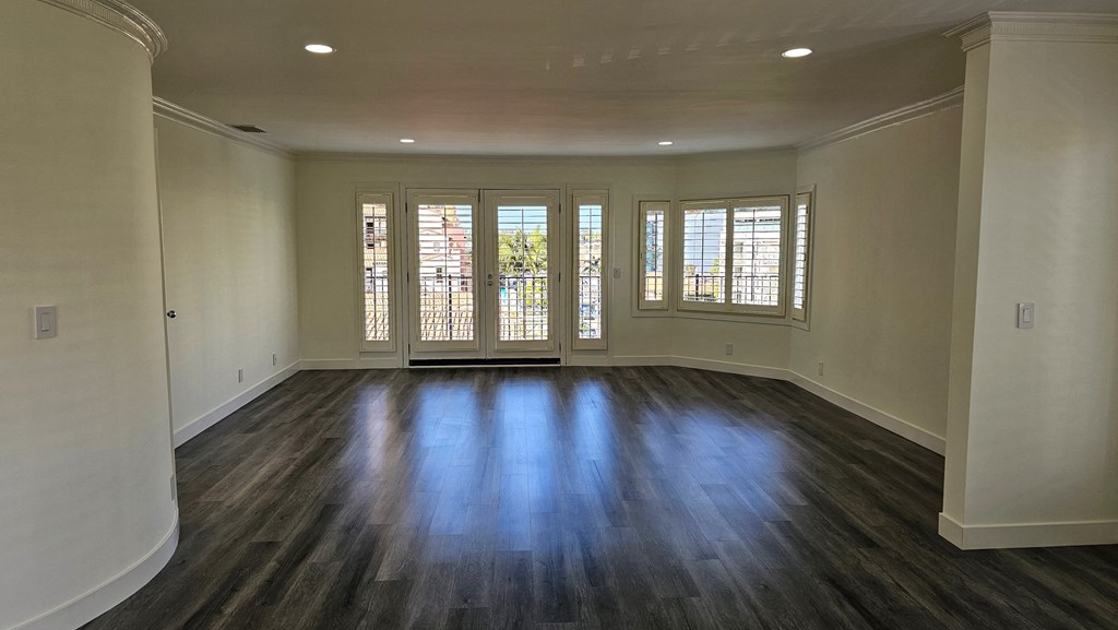 an empty living room with wooden floors and windows