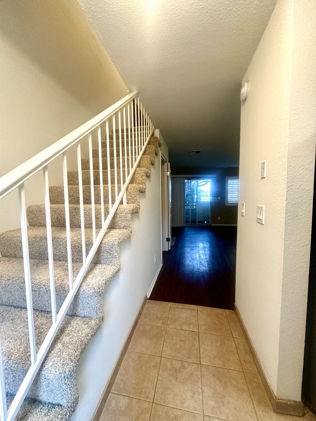 the hallway of a house with stairs and a carpeted floor