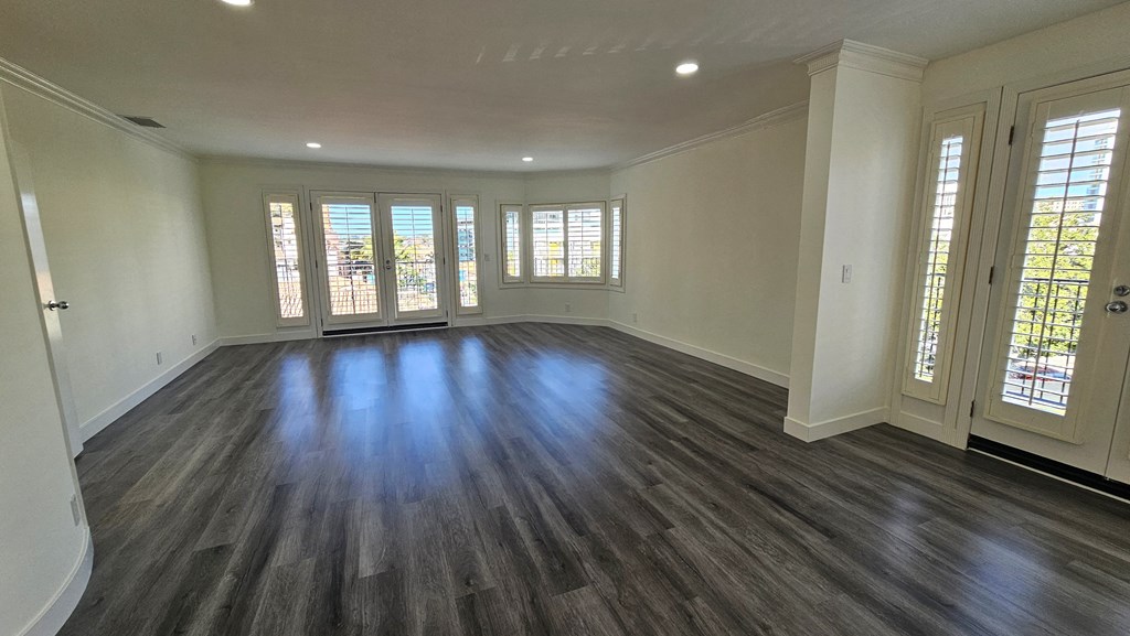an empty living room with wooden floors and windows