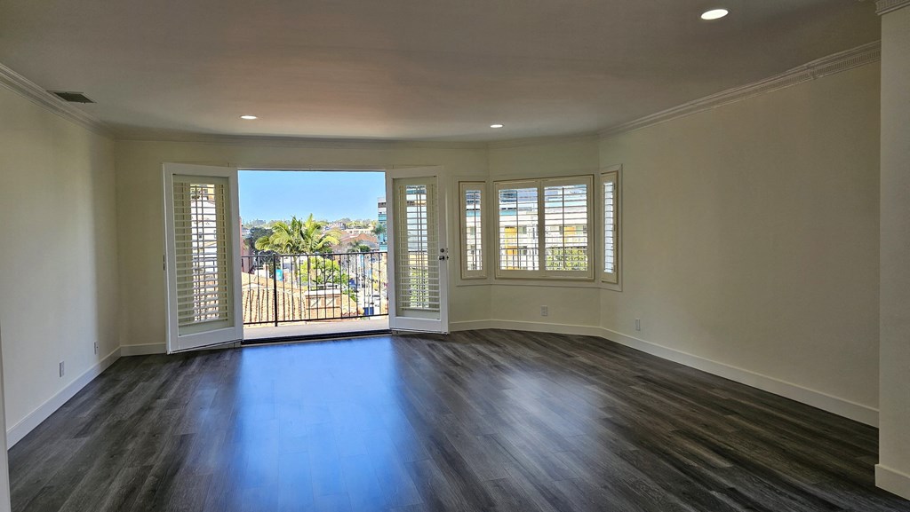 an empty living room with windows and a balcony