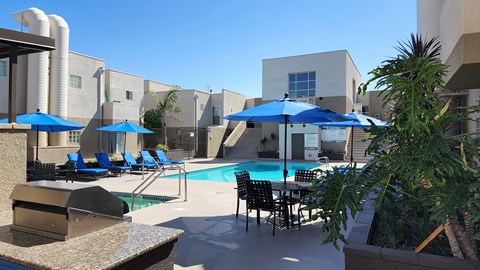 A pool area with blue umbrellas and chairs.