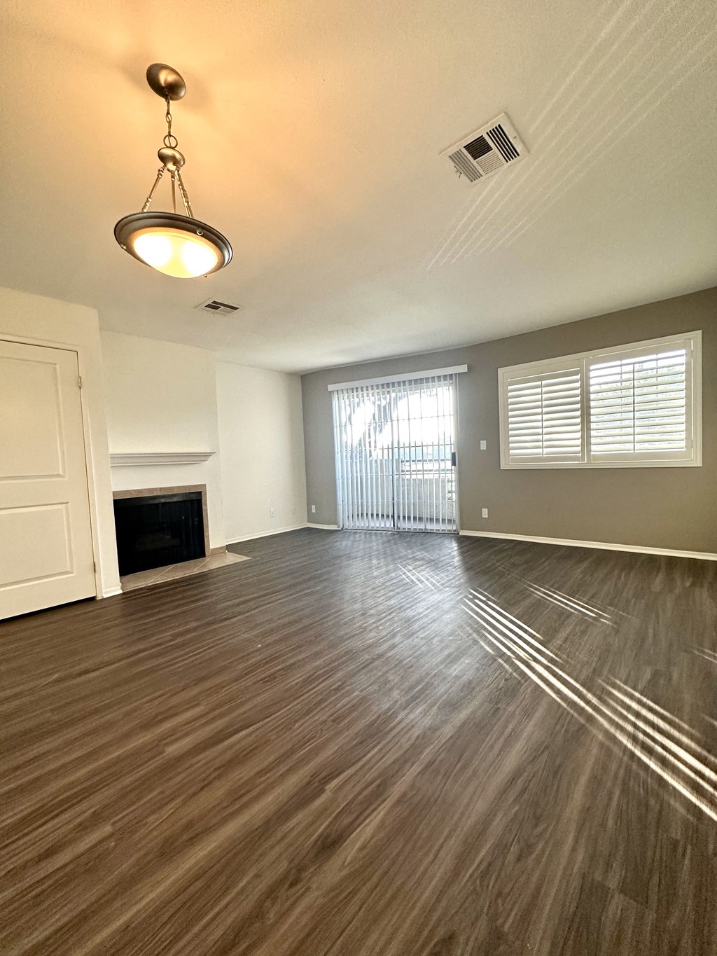an empty living room with wood flooring and a fireplace