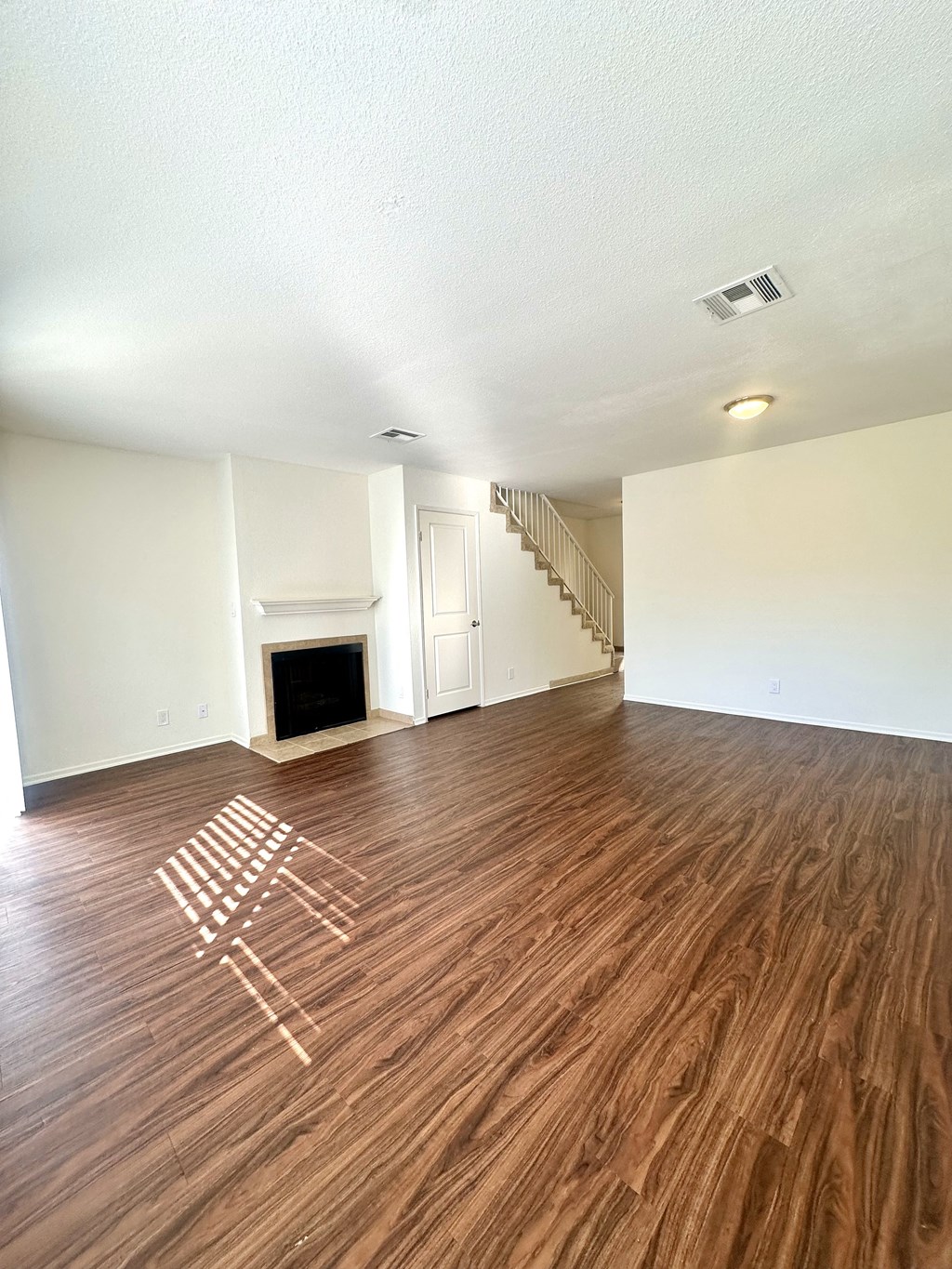 an empty living room with wood flooring and a fireplace