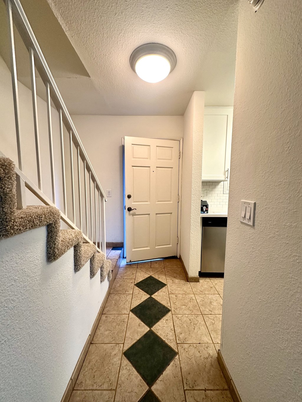 a hallway with stairs and a door to a kitchen