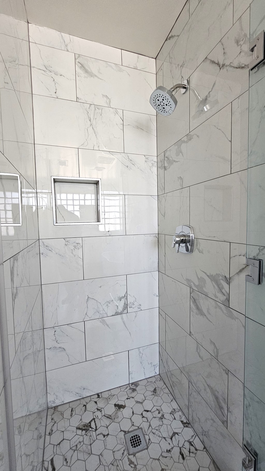 a large shower in a marble tiled bathroom
