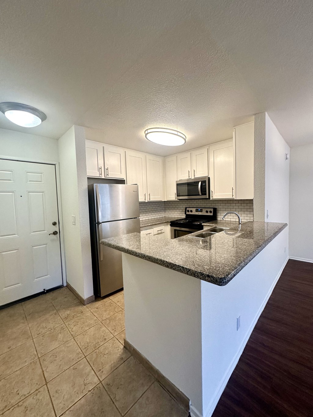 a kitchen with a granite counter top and a stainless steel refrigerator