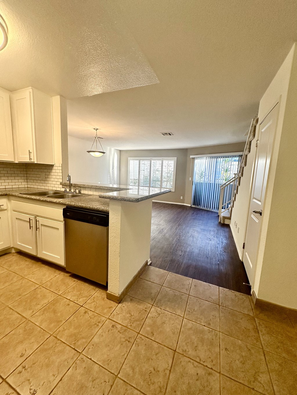 an open kitchen and living room with a stairway to a balcony