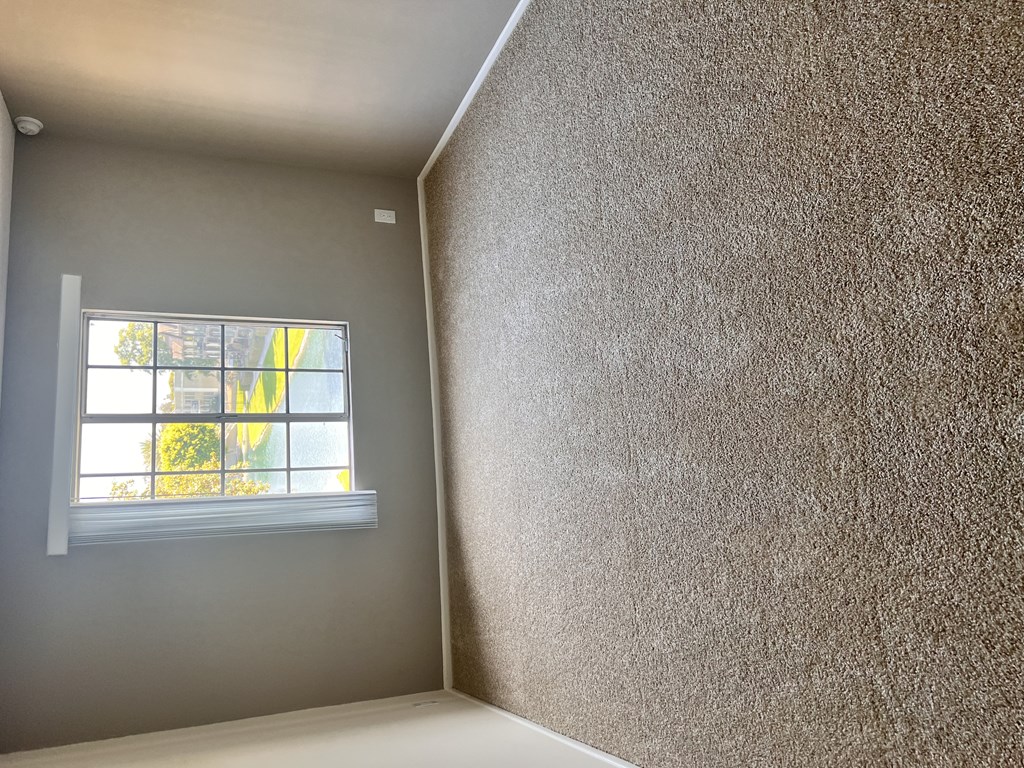 A room with a window and a wall covered in a textured material.
