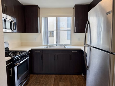 A kitchen with dark brown cabinets and a stainless steel refrigerator.