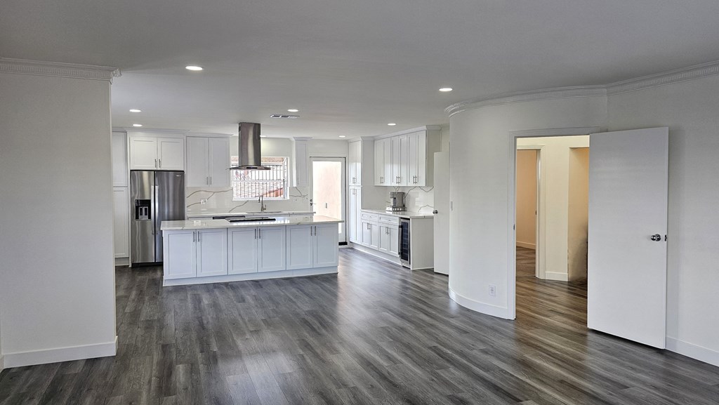 an open kitchen and living room with white cabinets and wood flooring