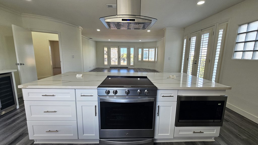 a large white kitchen with an island and stainless steel appliances