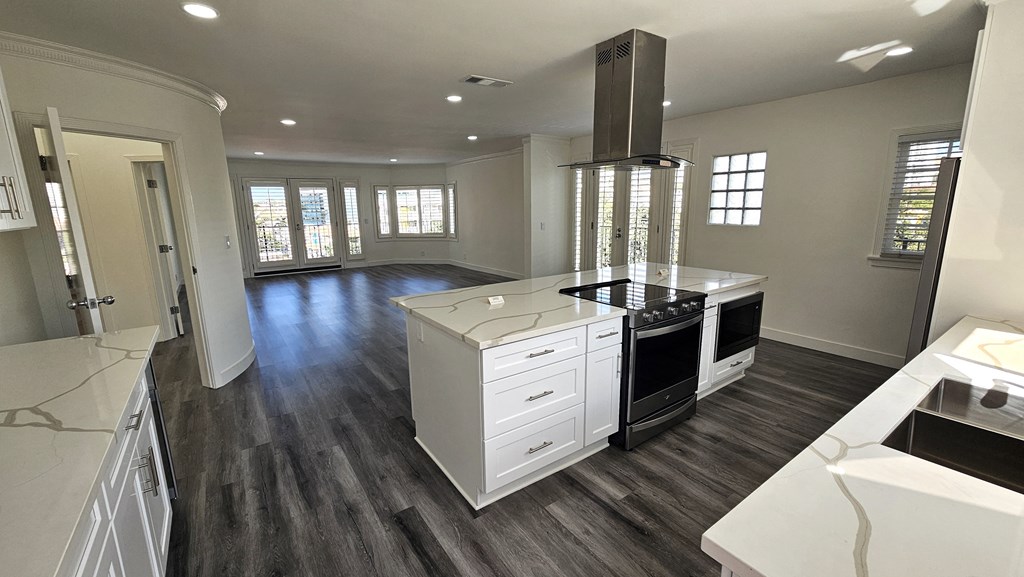 a kitchen with a center island and a stove and a living room
