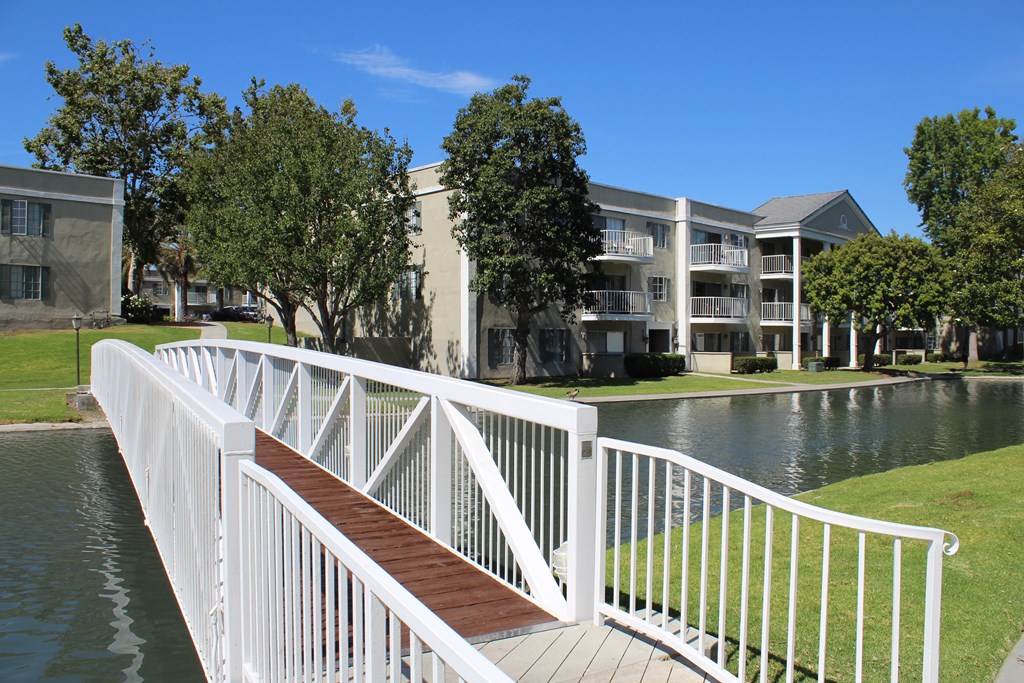 A white railing over a body of water with buildings in the background.