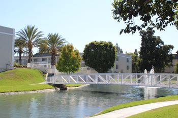 A white bridge over a body of water with a white fence and a white building in the background.