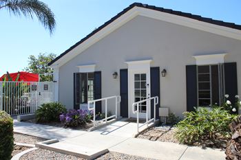 A white house with a black roof and a white fence.