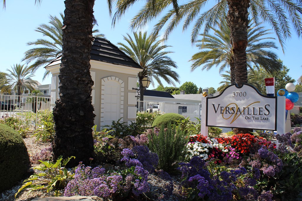 A Versailles sign is in front of a building and some trees.