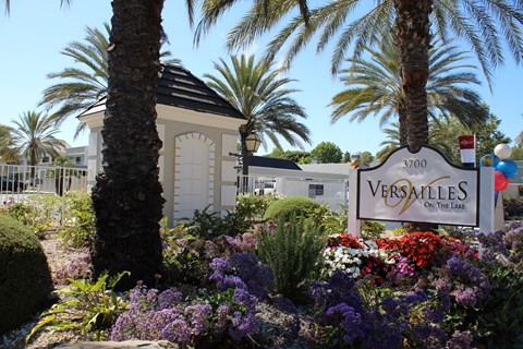A Versailles sign is in front of a building and some trees.