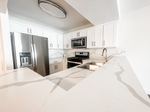 a kitchen with white cabinets and a stainless steel refrigerator
