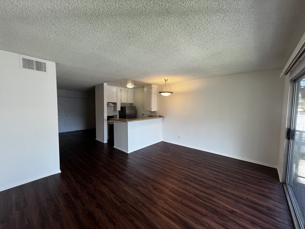 A room with wooden floors and a kitchenette.