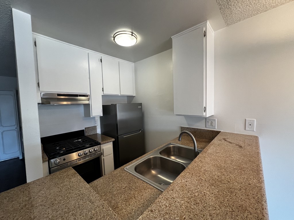 A kitchen with a sink and a stove top oven.