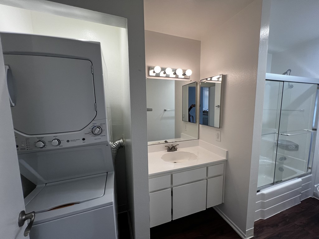 A white bathroom with a washer and dryer built in.
