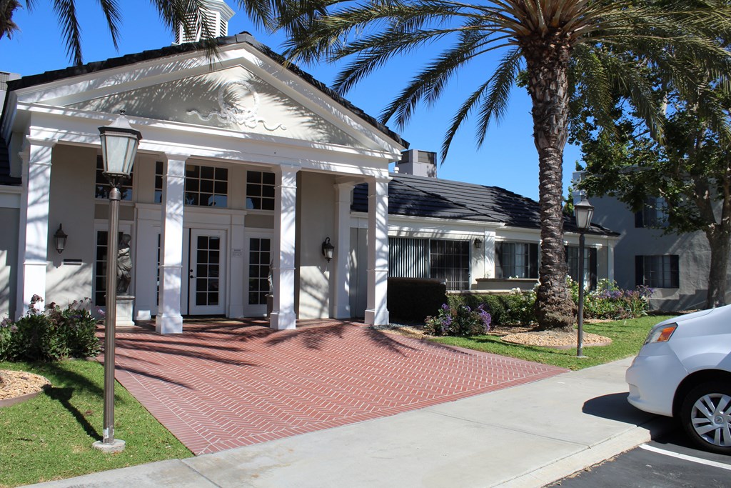 A white house with a black roof and a car parked in front.