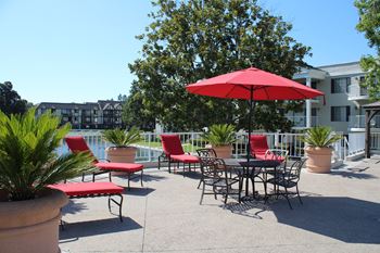 A red umbrella is in front of a table and chairs.