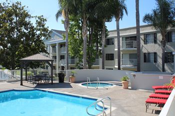 A pool with red chairs and a building in the background.