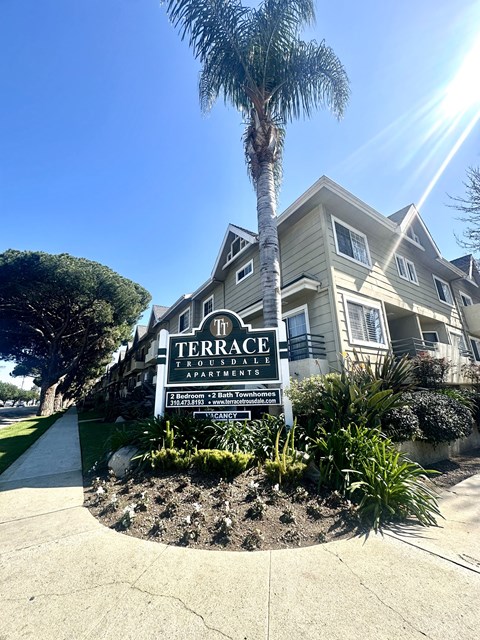 a house with a sign in front of a palm tree