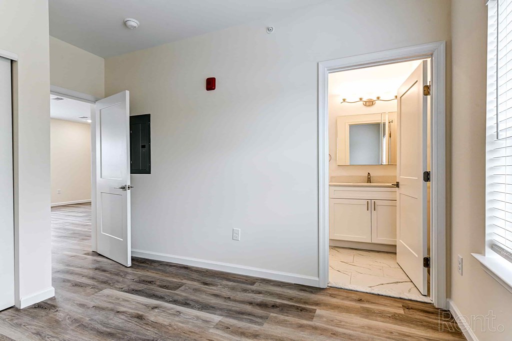 A room with a white door and a white wall with a red light switch.