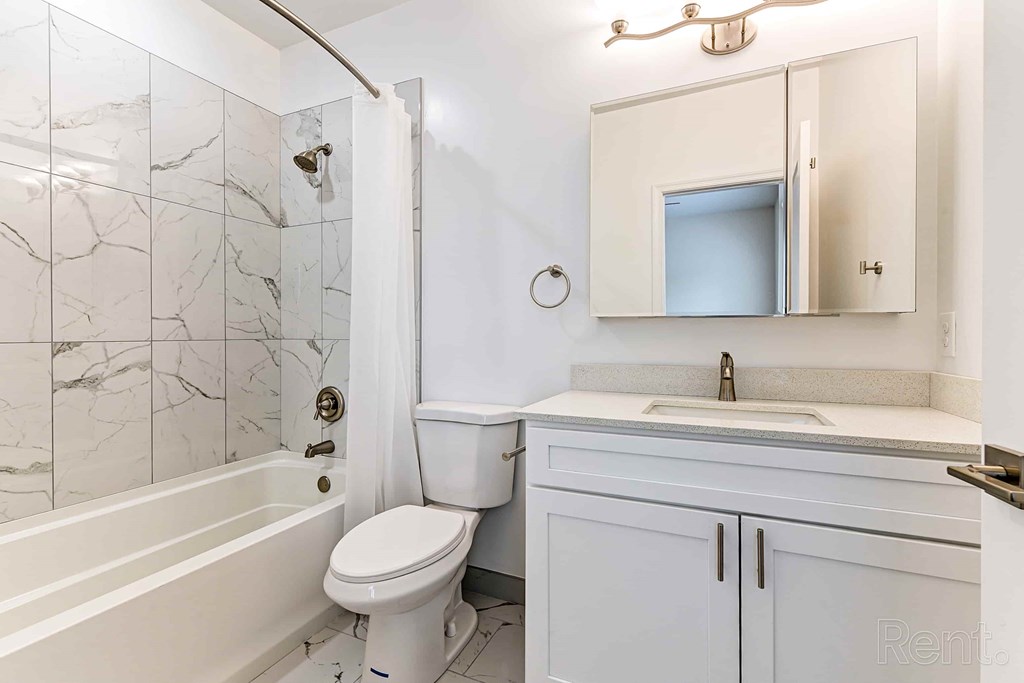 A white bathroom with a marble tile shower.