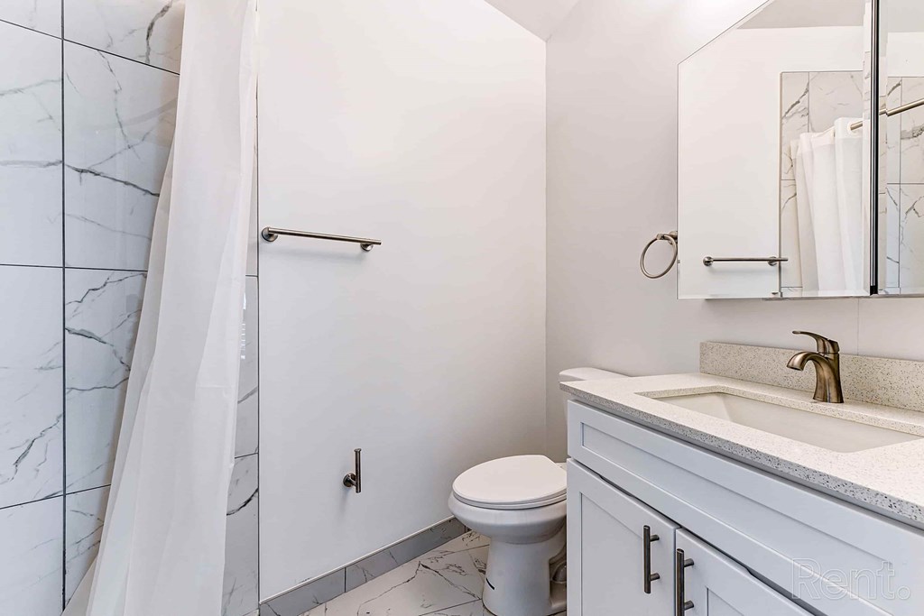 A white bathroom with a toilet, sink, and shower.