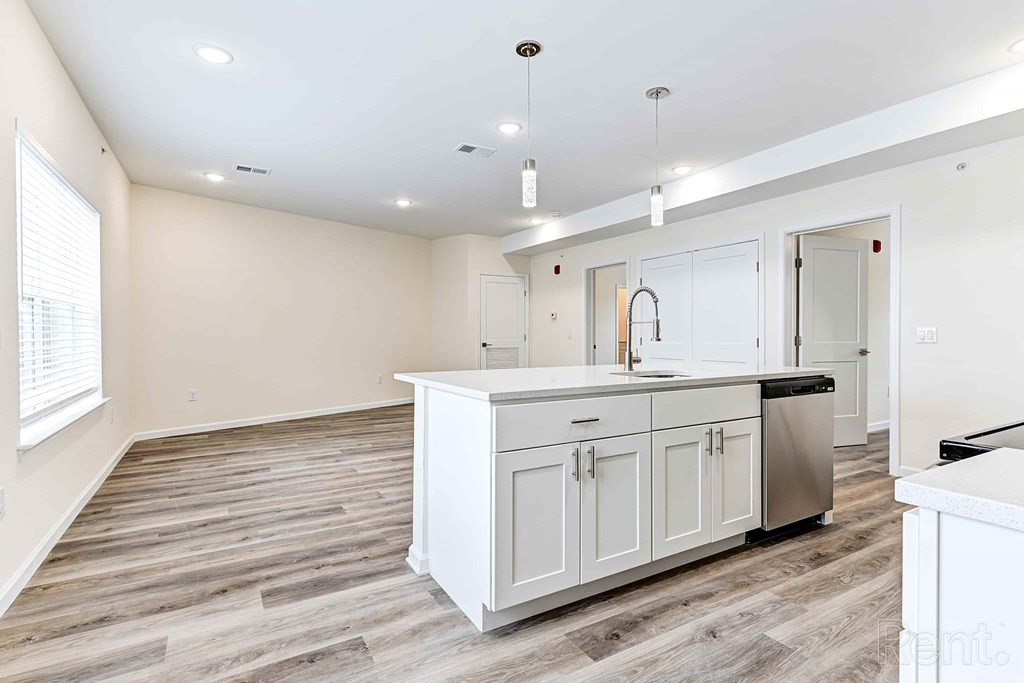 A kitchen with white cabinets and a wooden floor.