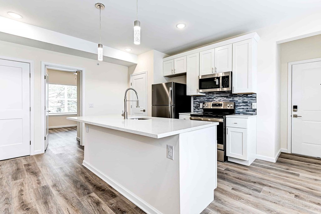 A kitchen with white cabinets and a black fridge.