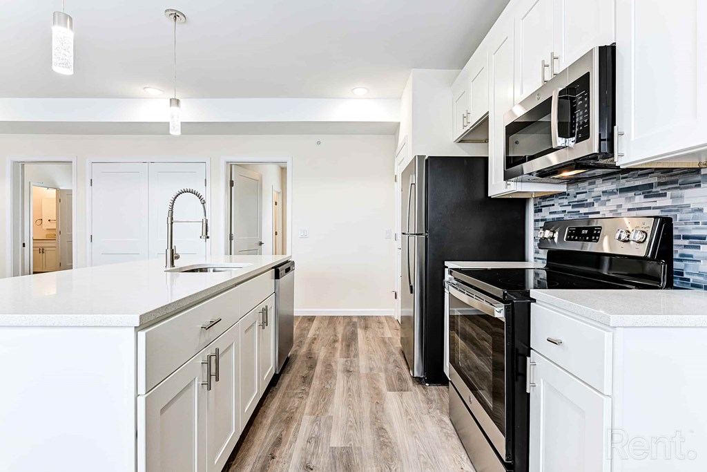 A kitchen with black appliances and white cabinets.