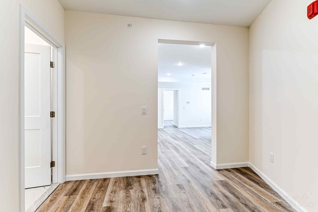 A room with a white door and a wooden floor.
