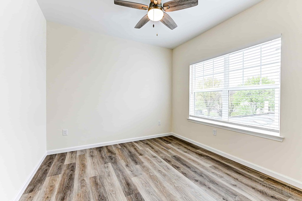 A room with a ceiling fan and a window with blinds.
