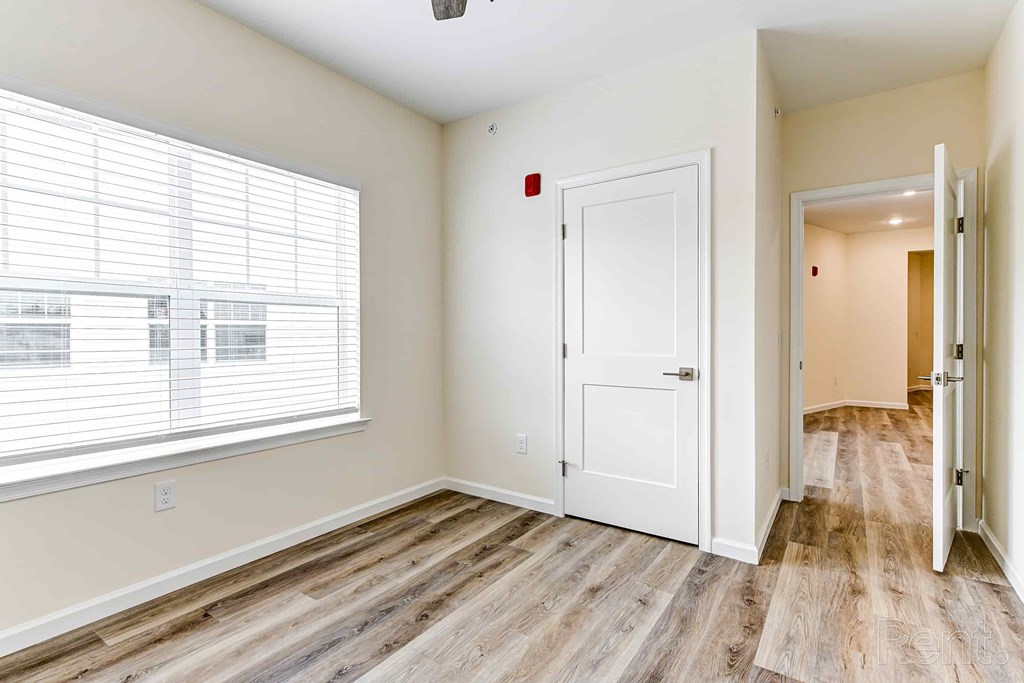 A room with a white door and a window with blinds.