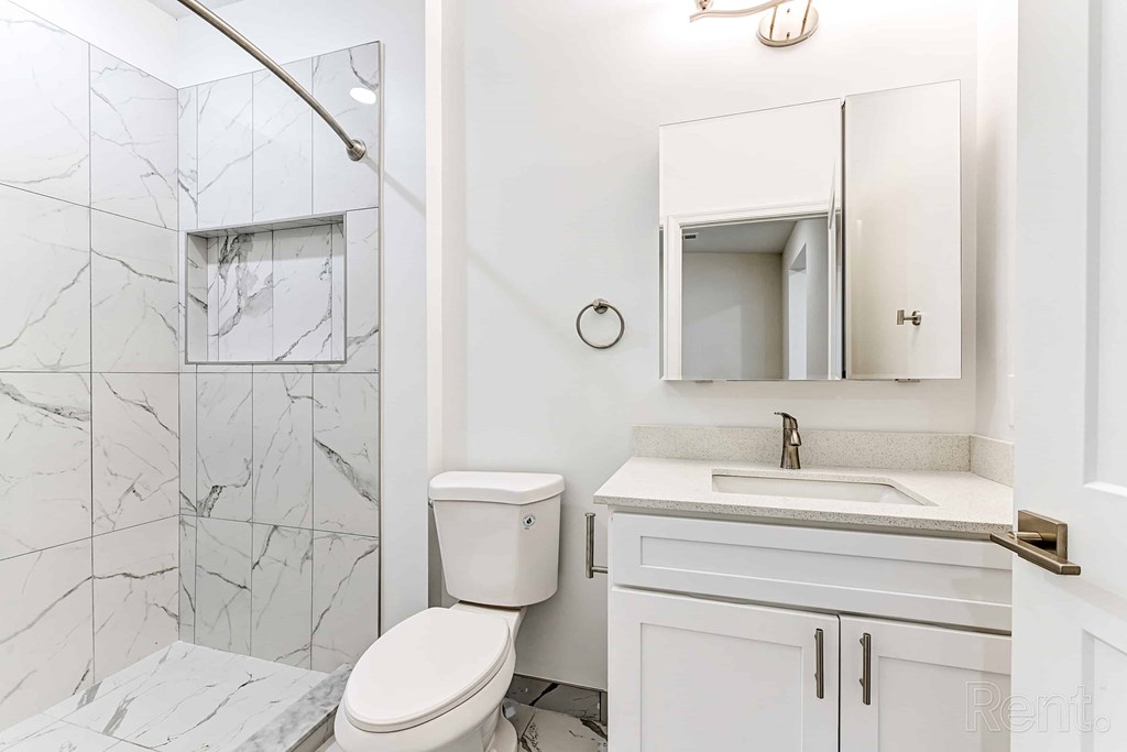 A white bathroom with a marble tile shower.