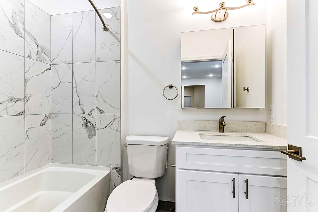 A white bathroom with a marble tile shower.