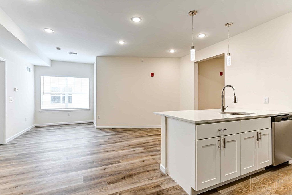 A kitchen with white cabinets and a wooden floor.
